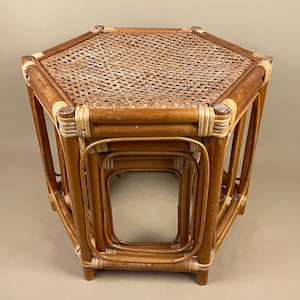 May include: A set of three rattan nesting tables. The largest table has an octagonal woven top. The tables are various sizes and have a warm, brown colour. The tables are suitable for indoor use. The tables are made of natural rattan.
