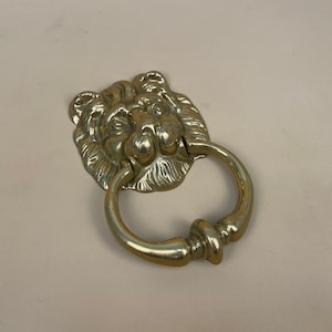 May include: A gold lion head door knocker with a round ring.