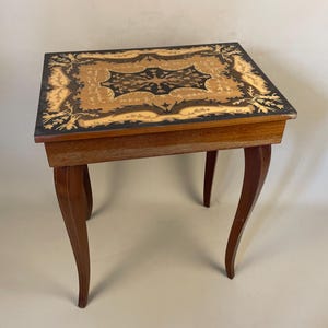 May include: An antique wooden side table with a rectangular top. The top has an inlaid design of light and dark wood. The table has four curved legs. The table is approximately 61 cm long, 41 cm wide, and 71 cm tall, suitable for a living room or hallway.