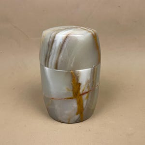 May include: A white ceramic mug with a black handle and the text "But First, Coffee" in a bold, black font. The mug is likely 325 ml in size and sits on a white surface.