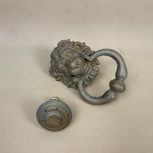 May include: A pair of antique door hardware pieces in a distressed silver finish. The larger piece is a lion's head door knocker with a ring handle. The smaller piece is a round door knob.