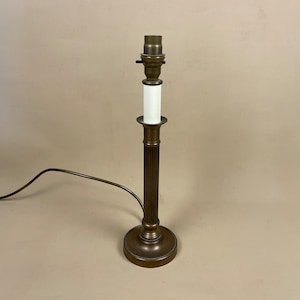 May include: A brass table lamp with a white shade and a fluted column base. The lamp has a cord and plug.