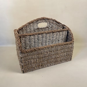 May include: A woven magazine holder with a brown and white pattern. The holder has a handle on the top and two compartments.