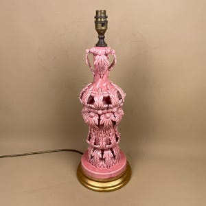 May include: A pink ceramic table lamp with a gold base. The lamp features a detailed, carved leaf design and a brass lamp holder. The lamp is approximately 51 cm tall.