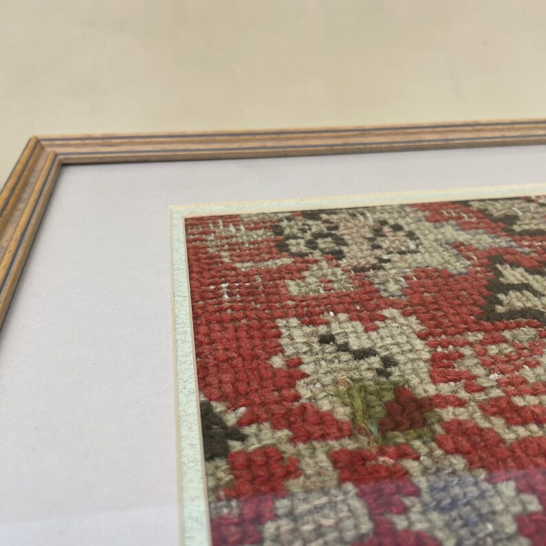 Pode incluir: Uma obra de arte emoldurada apresentando um close-up de um tapete com padr&otilde;es vermelhos, brancos e pretos. O tapete &eacute; tecido com detalhes intrincados e tem uma est&eacute;tica vintage.