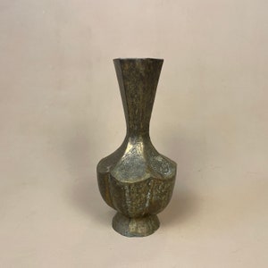 May include: A brass vase with intricate engraved designs. The vase has a wide base and a narrow neck.