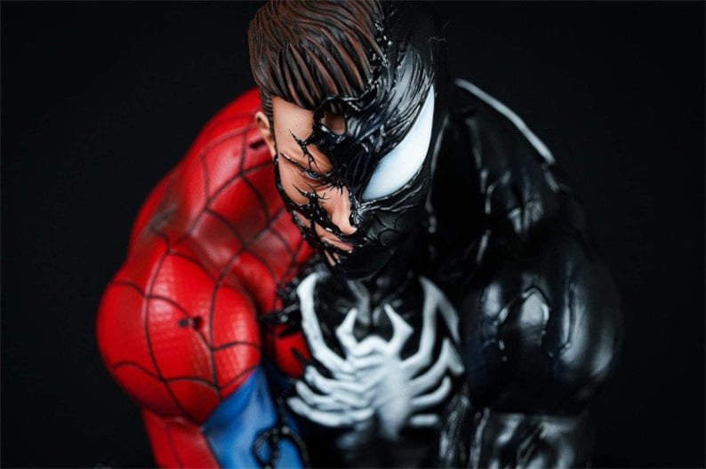 K&ouml;nnte beinhalten: Nahaufnahme einer schwarzen und roten Superheldenfigur. Die Figur ist eine Kombination aus Spider-Man und Venom, wobei Venoms Gesicht die H&auml;lfte von Spider-Mans Gesicht bedeckt. Die Figur ist detailliert mit komplizierten Spinnweben und Muskeldefinition.