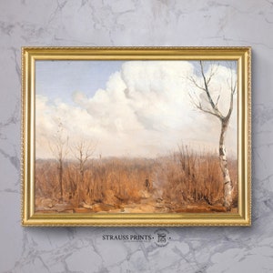 Op de afbeelding: Een ingelijst landschapsschilderij met een gouden, sierlijke lijst. Het kunstwerk toont een veld met hoog, droog gras en een pad dat naar een figuur in de verte leidt. Kale bomen en een bewolkte lucht zijn ook te zien. De tekst "STRAUSS PRINTS" staat onderaan.