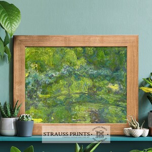 May include: A framed abstract painting of a green landscape with a light blue sky. The painting is in a wooden frame and is hanging on a teal wall. The painting is titled "Strauss Prints" and has a logo with a paintbrush and palette.