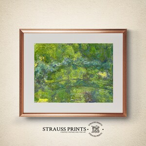 May include: A framed painting of a green landscape with a bridge over a pond. The painting is in a light wood frame and has a white mat.