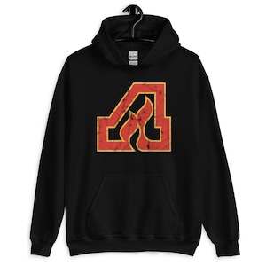 Puede incluir: Sudadera con capucha negra con un logotipo rojo y amarillo desgastado de una "A" estilizada con llamas.