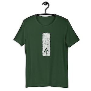 Puede incluir: Una camiseta verde oscuro con un gráfico rectangular blanco y desgastado del logotipo del Appalachian Trail. El logotipo es un triángulo blanco con una línea blanca que se extiende hacia abajo desde el punto del triángulo.