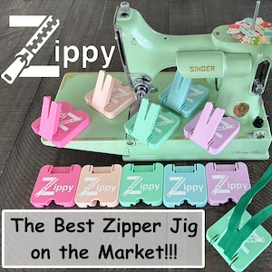 May include: A mint green Singer sewing machine with various coloured zipper jigs. The jigs are pink, peach, mint green, and light blue. The text "Zippy" and "The Best Zipper Jig on the Market!!!" are also visible.