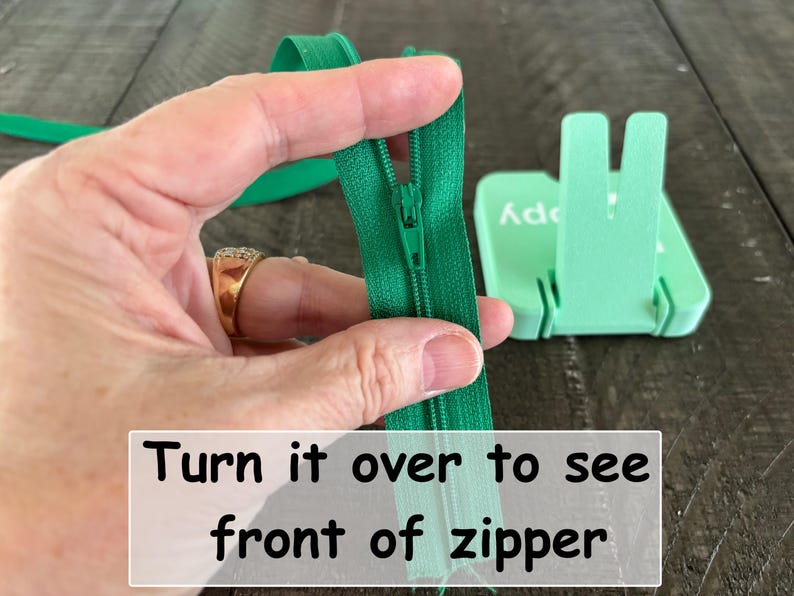 May include: A bright green zipper with a matching slider and pull tab, shown from the back side. The zipper tape is made of fabric, and the text "Turn it over to see front of zipper" is printed in black on a white rectangular overlay.