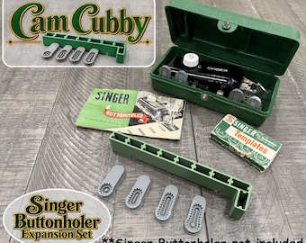 May include: A Singer buttonholer expansion set including a green plastic storage case, a black metal buttonholer attachment with a white dial, four grey plastic cams, a green instruction manual, and a small box labeled Singer Templates.