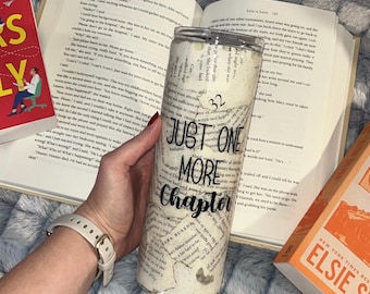 May include: A white tumbler with a black and white book page design. The tumbler has the text "Just One More Chapter" printed on it.