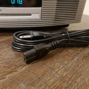 May include: A black electrical cord with a standard three-prong plug on one end and a two-prong plug on the other end.