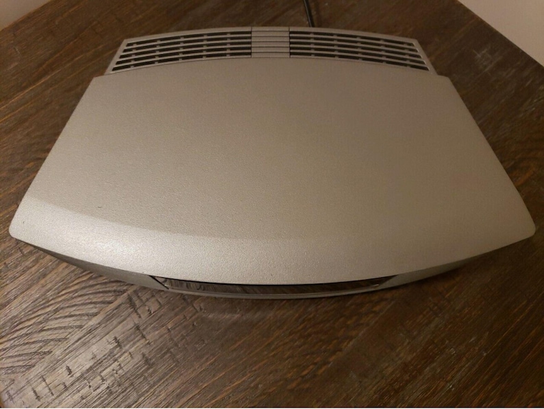 May include: A silver-colored DVD player with a curved design and a slot for a disc on the front.