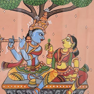 May include: A vibrant Indian painting depicting two figures under a tree. One figure, blue-skinned, plays a flute, while the other, yellow-skinned, holds a leaf. The scene is set against a peach background with a water scene at the bottom.