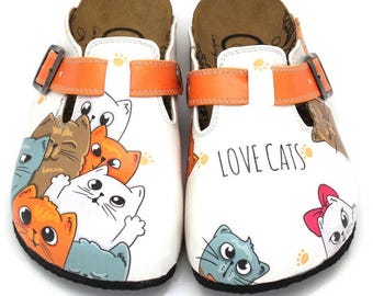 May include: A pair of white slip-on clogs featuring a colorful cartoon cat print and the text LOVE CATS. Each shoe has an adjustable orange strap with a metal buckle, a brown footbed, and a black sole. The cats are depicted in various colors.