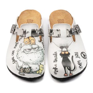 May include: White clogs with black soles and adjustable straps. Each clog features a unique cartoon design with cats and text. One clog says "You can not escape" and the other says "Make Biscuits not War".
