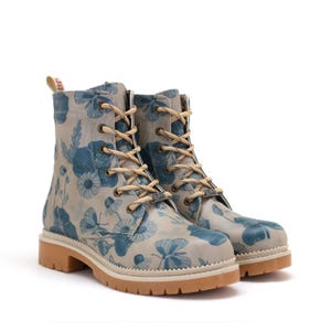 Könnte beinhalten: Knöchelstiefel mit floralem Muster. Die Stiefel haben einen hellgrauen Hintergrund mit blauen Blumenmustern, beigefarbenen Schnürsenkeln und einer beigefarbenen Sohle. Sie haben einen robusten Outdoor-Stil, mit einer Absatzhöhe von ca. 3 cm.