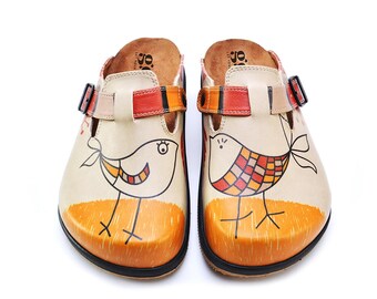 May include: Pair of beige leather clogs with a whimsical bird design. The clogs feature orange and red accents on the straps and toe, with a black sole. Each clog has a unique bird illustration in black outline with colorful details.