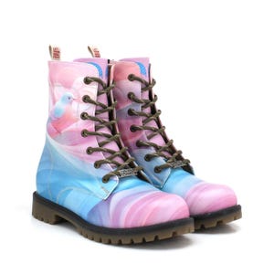 Op de afbeelding: Kleurrijke combat boots met een pastel ontwerp. De laarzen hebben een verloop van roze, blauwe en paarse tinten, met een vogelillustratie aan de zijkant. Ze hebben bruine veters en zolen, met de tekst "LET YOUR SOUL FREE".