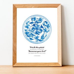 Op de afbeelding: Een ingelijst print met een blauw en wit bloemenmotief op een bord. De quote "Was de plaat niet omdat hij vies is, maar omdat je de persoon liefhebt die hem als volgende zal gebruiken." staat onder het bord gedrukt. De quote wordt toegeschreven aan St. Teresa van Calcutta.