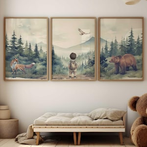May include: Three framed watercolour prints showing forest scenes. One print features a fox, another a child, and the third a bear. The prints are displayed above a daybed and a large teddy bear in a bright room.