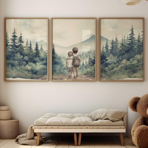 May include: Three framed watercolor paintings depicting a forest scene with two figures standing in the middle frame. The figures are facing away from the viewer and appear to be children. The paintings are hung on a white wall above a light brown bench.