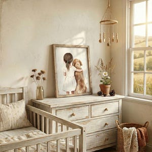 May include: A framed watercolor print depicts a young person hugging a golden retriever. The artwork is displayed on a distressed white wooden dresser. A baby crib with a floral pillow is in the foreground. A decorative mobile hangs from the ceiling.