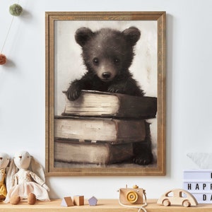 May include: A framed print of a brown bear cub sitting on a stack of old books. The bear is looking at the viewer with a curious expression. The print is in a rustic wooden frame.