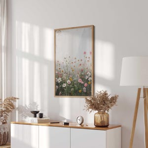 May include: A framed print of a watercolor painting featuring a field of pink, white, and yellow wildflowers against a light gray background.