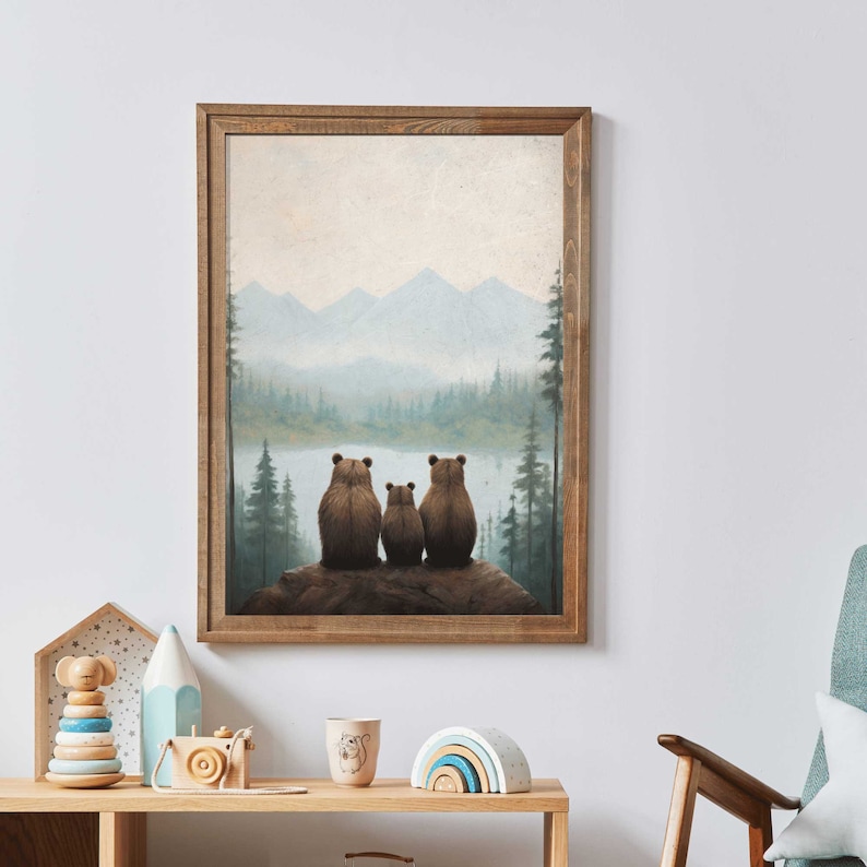 May include: A framed print of a painting depicting three brown bears sitting on a rock overlooking a lake and mountains in the distance. The sky is a light blue with white clouds. The painting is in a rustic wooden frame.