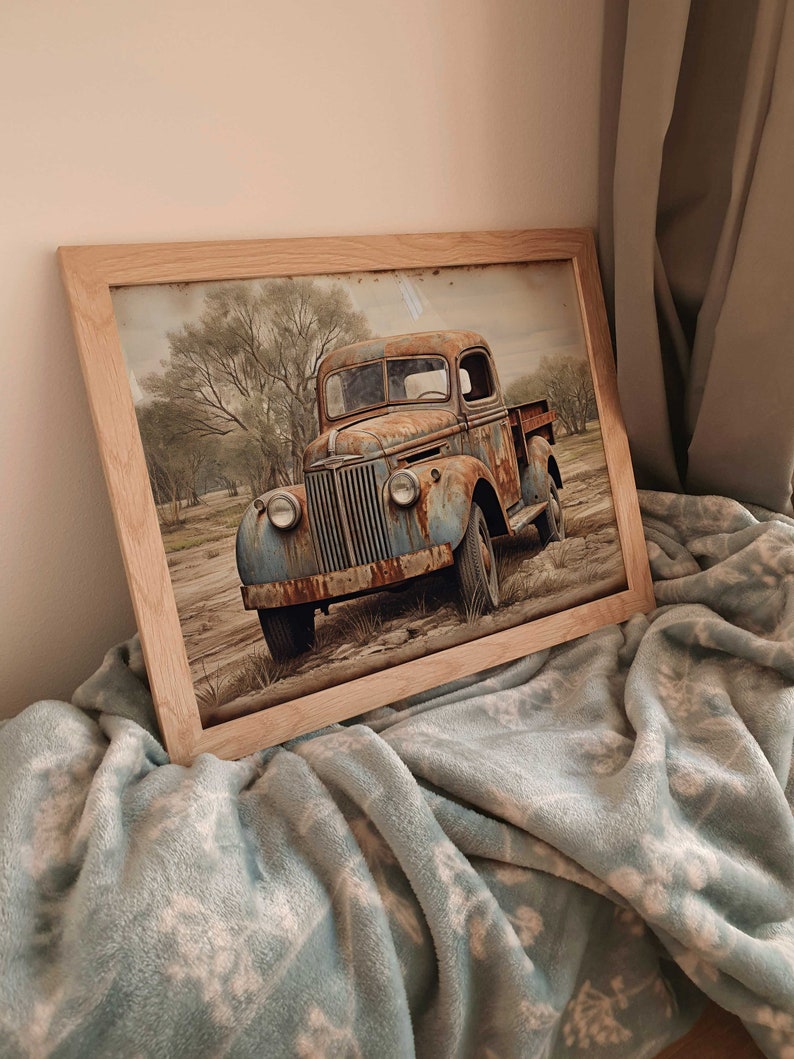 May include: A framed print of a rusty blue pickup truck parked in a field with trees in the background.