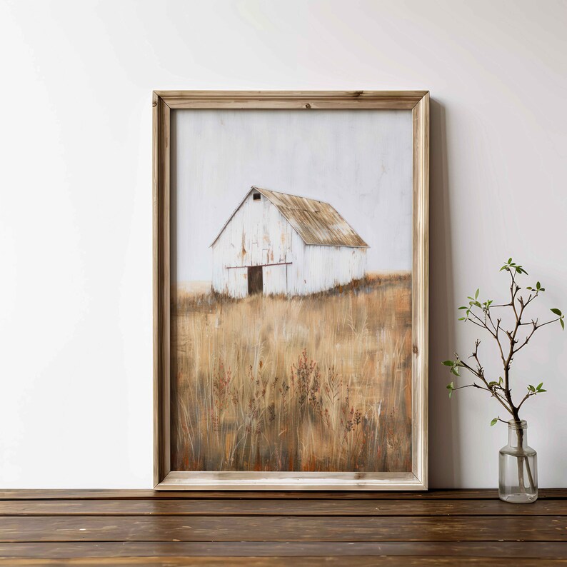 May include: A framed painting of a white barn in a field of tall grass. The barn has a rusty metal roof and a single wooden door. The grass is a mix of brown and yellow.