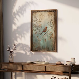 K&ouml;nnte beinhalten: Ein gerahmter Vintage-Druck eines Vogels, der auf einem Zweig mit zarten Blumen sitzt. Der Hintergrund ist in einem verblassten Blau und Gr&uuml;n mit einer abgenutzten Textur gehalten. Der Rahmen ist aus einfachem braunem Holz.