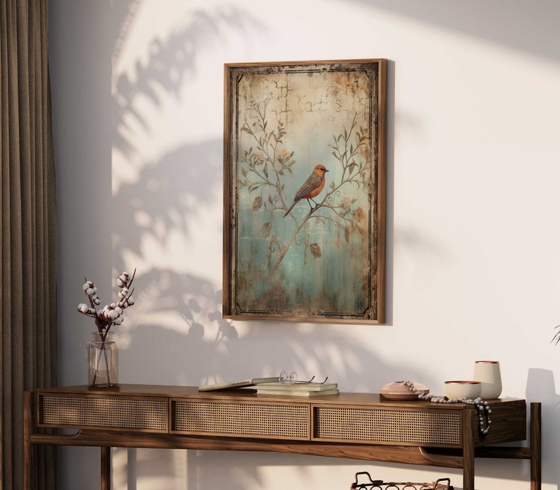 K&ouml;nnte beinhalten: Ein gerahmter Vintage-Druck eines Vogels, der auf einem Zweig mit zarten Blumen sitzt. Der Hintergrund ist in einem verblassten Blau und Gr&uuml;n mit einer abgenutzten Textur gehalten. Der Rahmen ist aus einfachem braunem Holz.