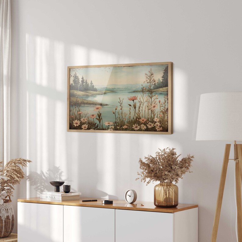 Puede incluir: Una pintura enmarcada que representa una escena de lago con &aacute;rboles en el fondo y flores rosas en primer plano. La pintura tiene un estilo vintage.