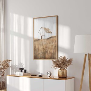 May include: A framed painting of a white barn in a field of tall, dry grass. The barn has a brown door and a brown roof. The grass is a mix of brown and gold.