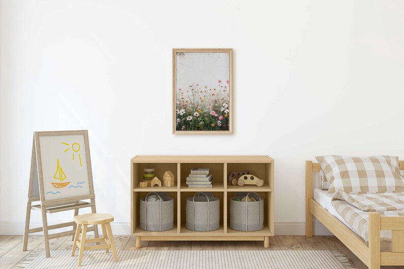 May include: A light wood bookshelf with six cubbies, each containing a storage basket or decorative items. The bookshelf is in a room with a white wall, a wooden easel with a drawing of a sailboat and sun, a small wooden stool, and a wooden bed with a checkered patterned comforter.
