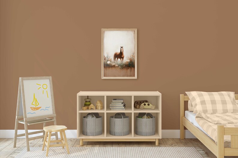 May include: A framed print of a brown horse in a field is displayed above a wooden storage unit with grey fabric bins. A child's easel with a drawing of a sailboat and a small wooden stool are in the foreground. A bed with a checked duvet is on the right.
