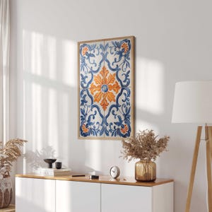 May include: A framed print of a blue and orange floral tile pattern. The tile pattern is a traditional design with intricate details. The print is framed in a natural wood frame.