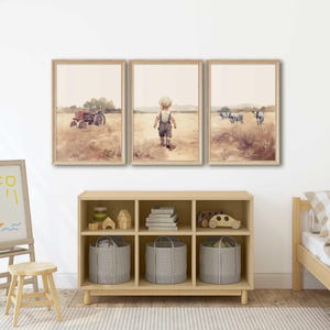 May include: A set of three framed watercolour prints depicting a rural scene. The first print shows a red tractor in a field, the second print shows a young boy walking in a field, and the third print shows a herd of cows in a field.