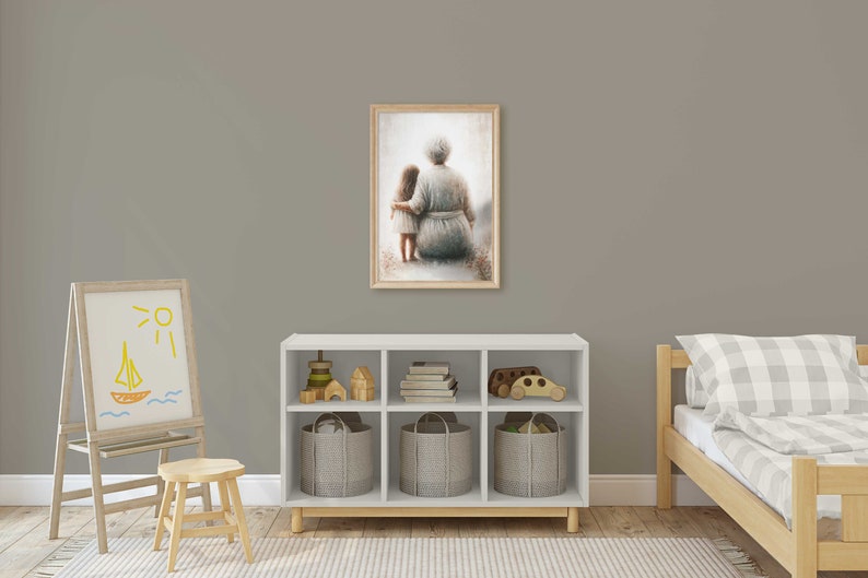 May include: A framed painting of an older woman and a young girl sitting together, both wearing light blue dresses. The painting is set against a light gray wall in a child's room with a white bookshelf, a wooden easel, and a wooden bed.