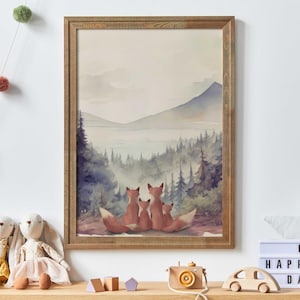 May include: Framed watercolour print depicting a family of foxes in a mountain scene. The artwork uses a soft palette of blues, greens, and browns. The framed art is displayed on a shelf with toys and a light box.