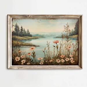 Puede incluir: Una pintura enmarcada que representa una escena de lago con un bosque en el fondo. El lago es azul y el bosque es verde. Hay flores rosas y blancas en primer plano.