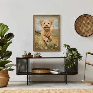 May include: A framed painting of a golden retriever puppy running through a field of wildflowers. The puppy is smiling and has its tongue sticking out. The background is a green field with a blue sky and white clouds.