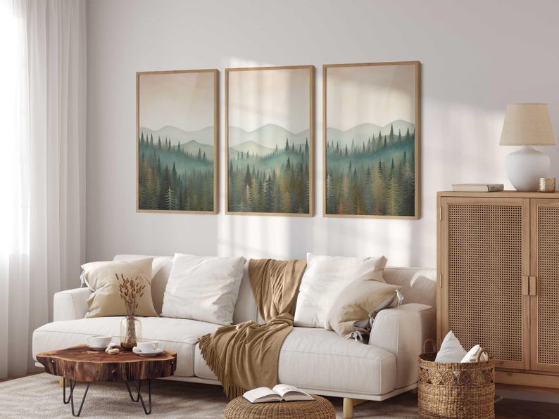 May include: Three framed landscape prints of a forest scene with a white couch, a wooden coffee table, a woven basket, and a wooden cabinet with a woven door in a living room setting.